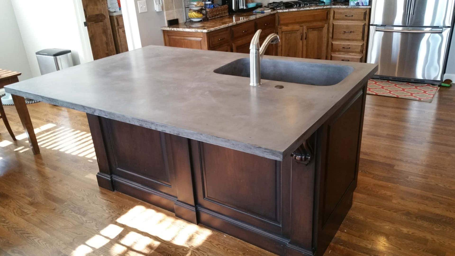 concrete counter top island in residential kitchen with large sink basin