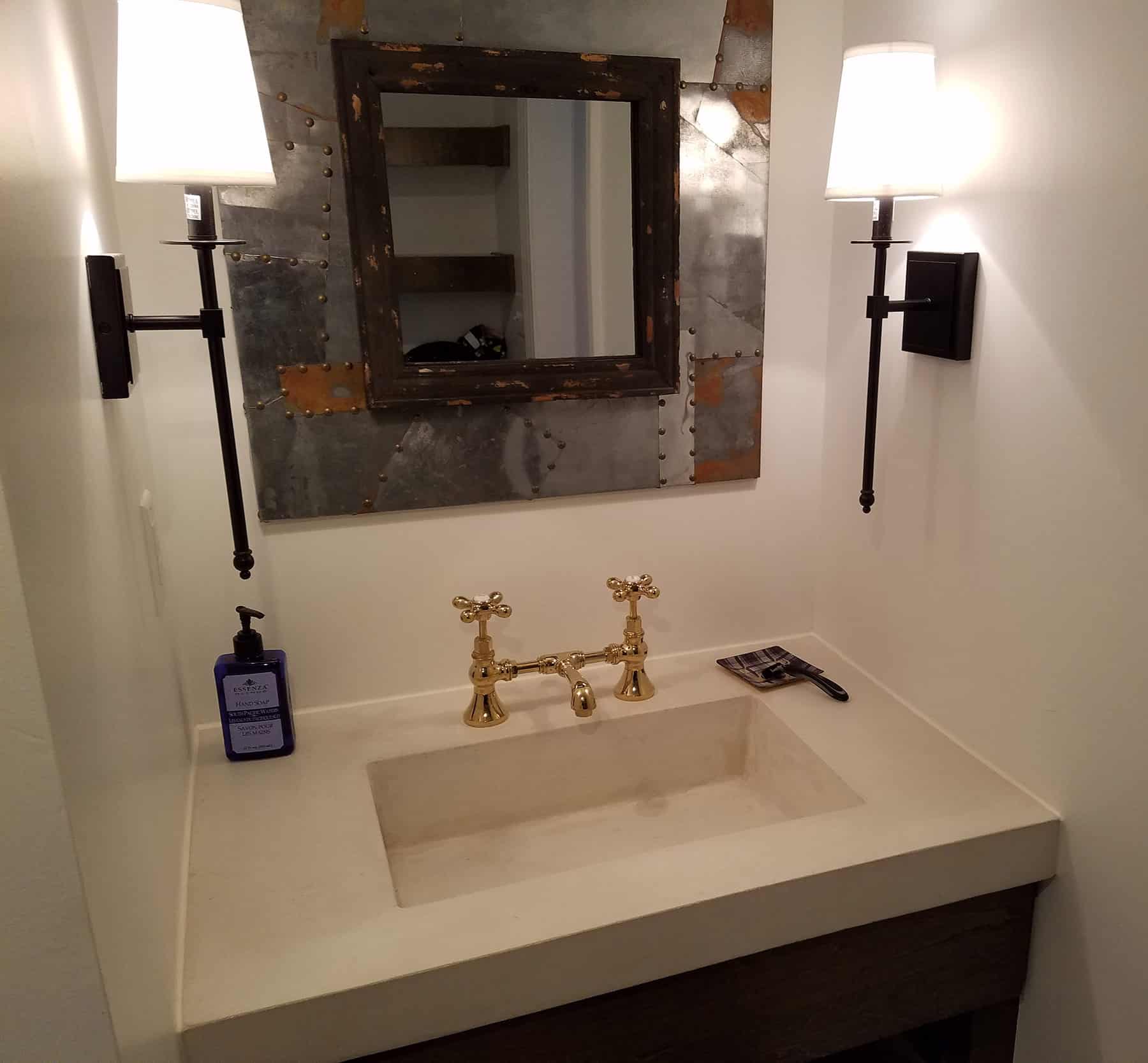 white concrete vanity with gold faucet in residential bathroom