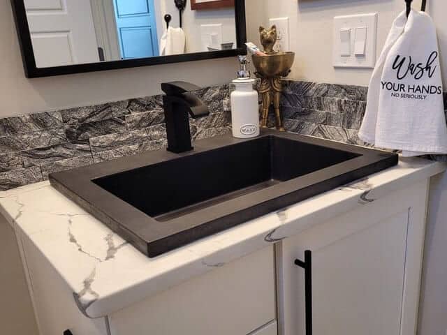 vessel sink, black, on white granite, in bathroom